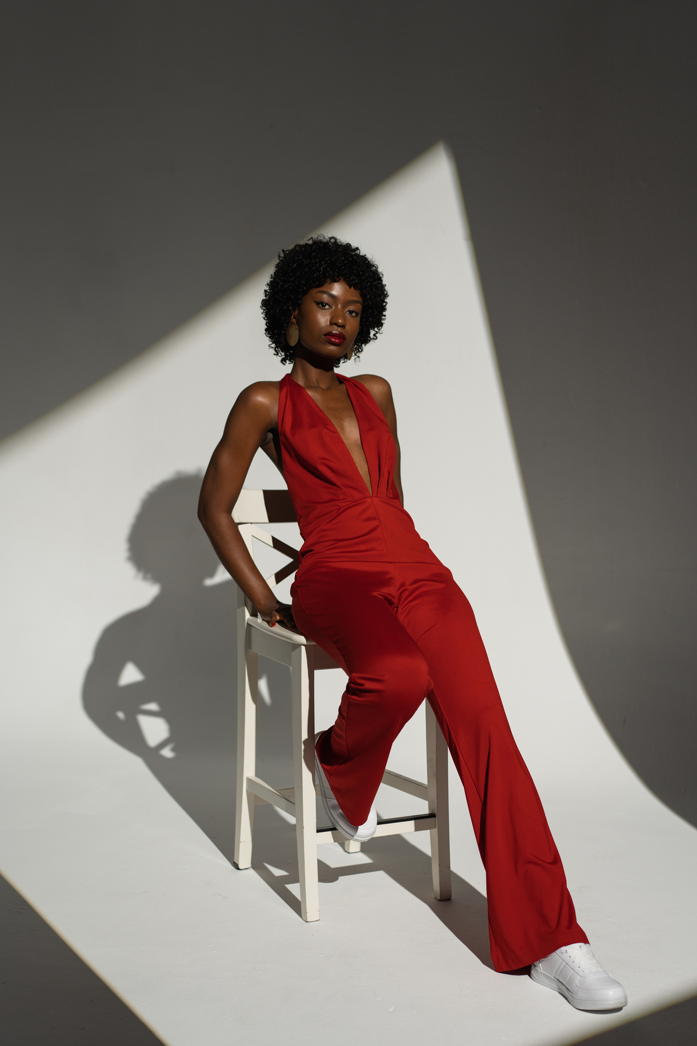 Stylish Woman in Red Jumpsuit Sitting on a Chair